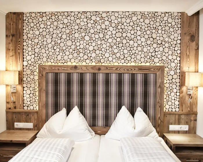 Bett vor Wand mit verschiedensten kleinen Hölzern als Designelement