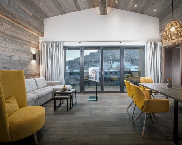 Großzügiges, modernes Wohnzimmer mit Couch, Sessel und Essbereich mit verschiedenen gelben Designelementen