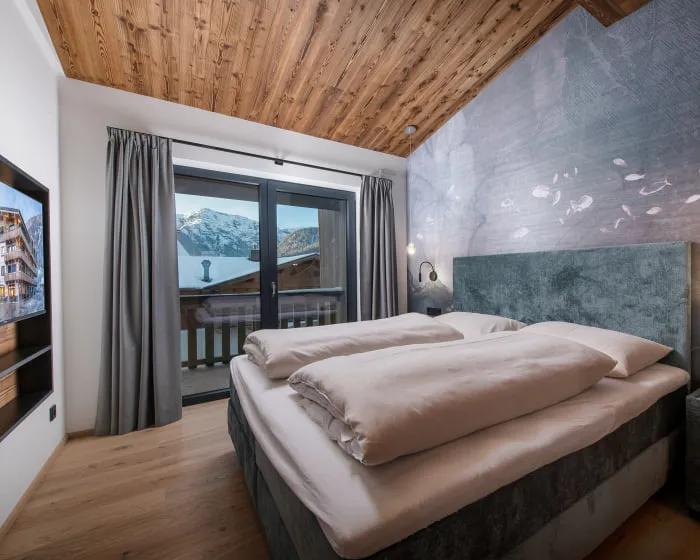 Schlafzimmer mit großem Doppelbett vor Designtapete in grau