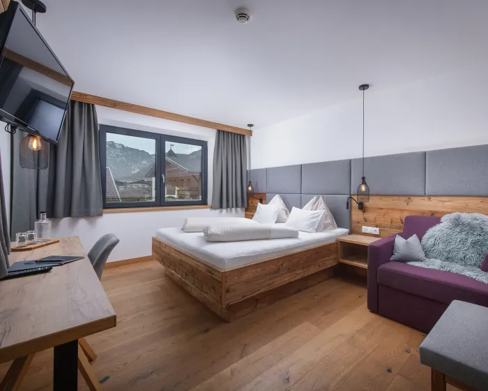 Großzügiges, modernes Schlafzimmer mit Doppelbett, Tisch und Sessel